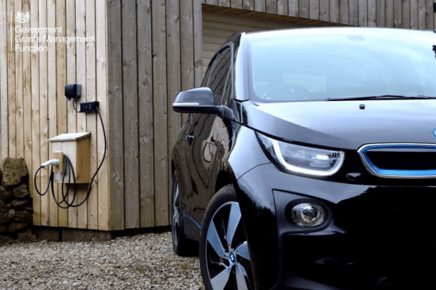 An electric charge-point on a wall - next to a black car